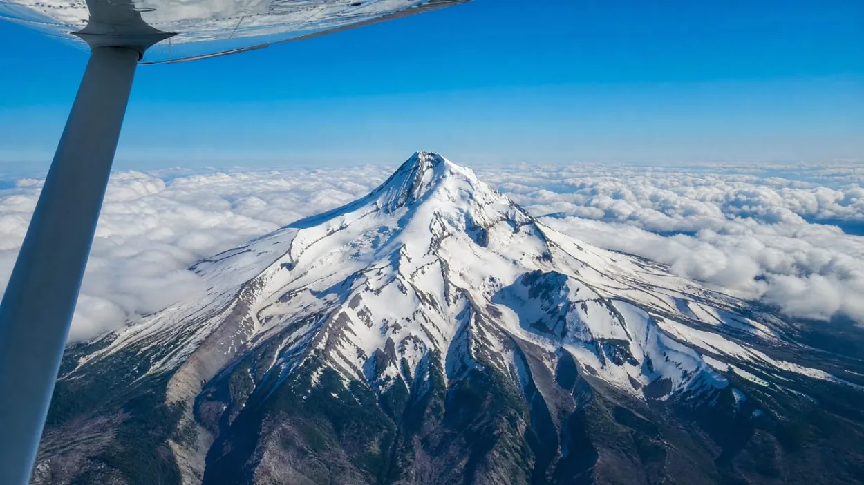 Mount Hood seen from the window of a small airplane above the clouds