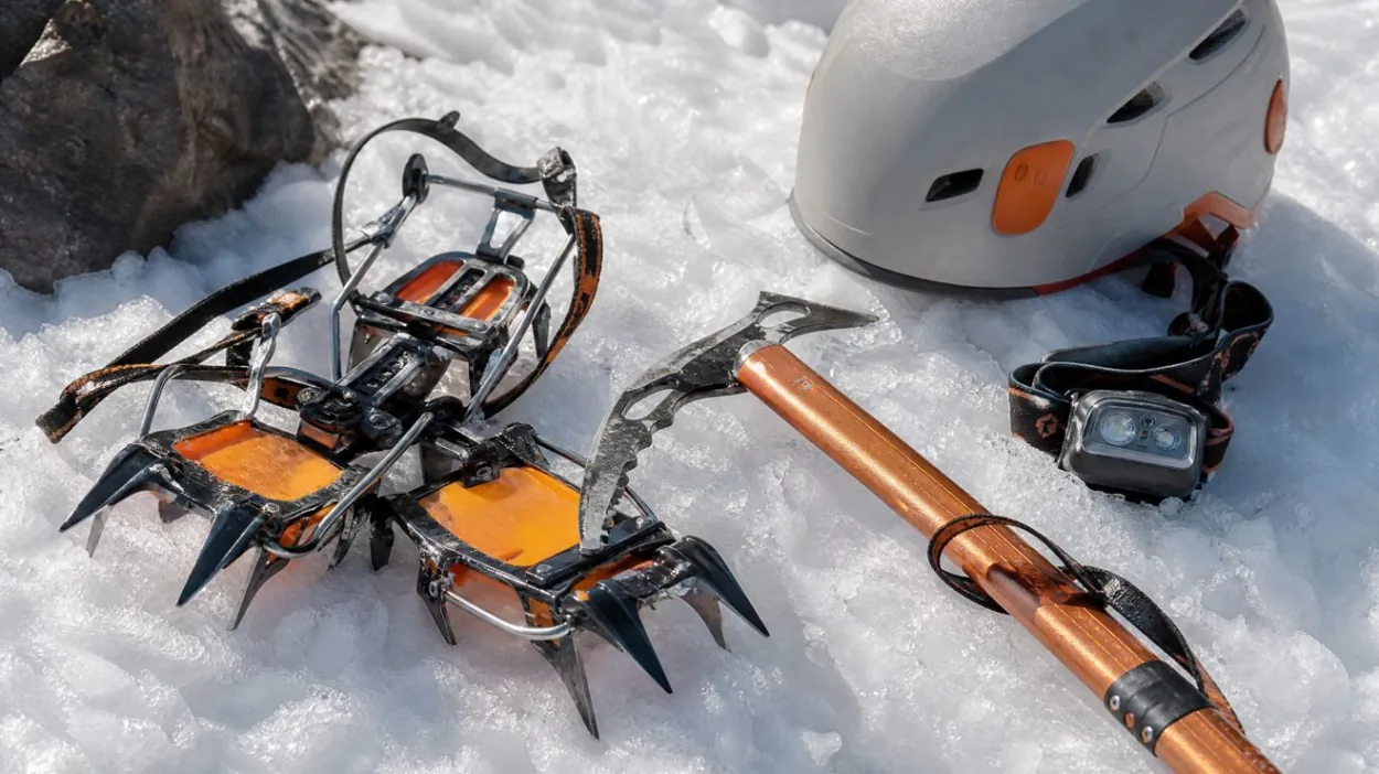 Steigeisen, Eispickel und Helm auf festem Frühjahrsschnee